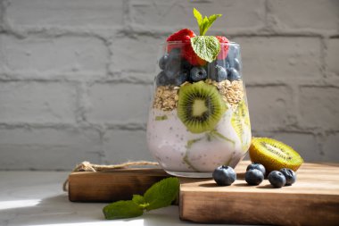 Yogurt, chia seeds, blueberries, strawberries, raspberries, mint, kiwi on a light background