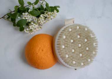 Massage brush, orange on a light background