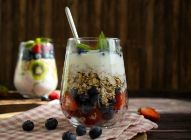 Yogurt, chia seeds, blueberries, strawberries, raspberries, mint, kiwi on a dark background