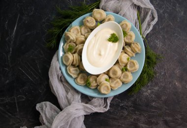 Dumplings with sour cream and herbs on an old background