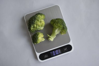 Fresh broccoli kitchen scale on a light background