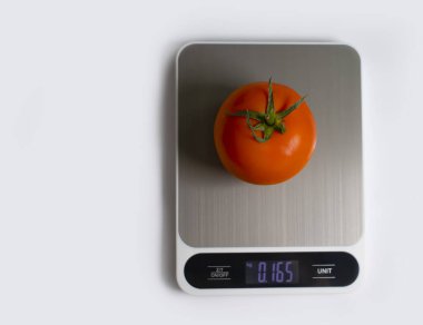 Electronic kitchen scales, tomato on a light background