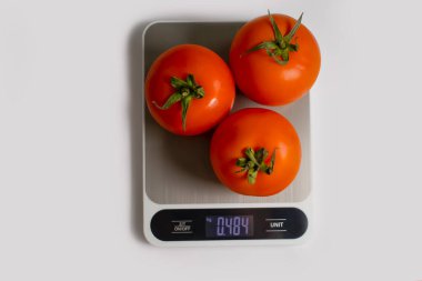Electronic kitchen scales, tomato on a light background