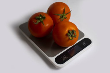 Electronic kitchen scales, tomato on a light background