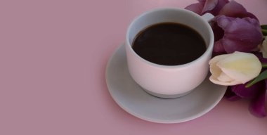 Bir fincan kahve, renkli arka planda lale çiçeği.