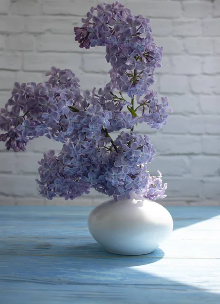 Bouquet of lilacs in a vase on a light background