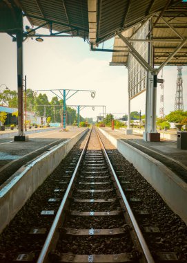 Parlak güneşli bir günde tren istasyonunda uzanan boş demiryolu rayları. Seyahat, yolculuk, ulaşım ve yalnızlık temaları için mükemmel..