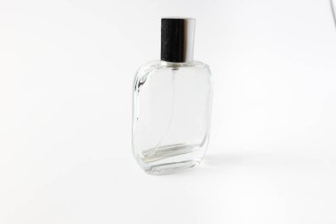 Elegant transparent perfume bottle with shiny chrome cap, photographed at an angle on white. Great for branding mockups, cosmetic ads, or minimalist product visuals. Isolated on white. 