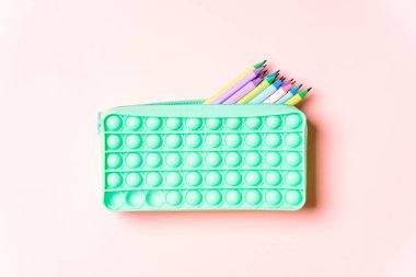 Pembe arka planda renkli kalemleri olan bir kalem kutusu..