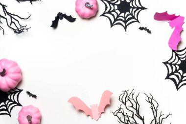 Beyaz arka planda pembe balkabakları, yarasalar ve örümcek ağları.