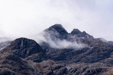 Bulutlu bir gökyüzünde bir dağ zirvesi