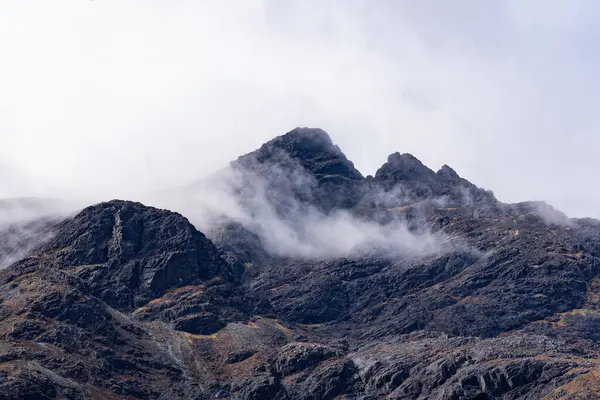 Bulutlu bir gökyüzünde bir dağ zirvesi