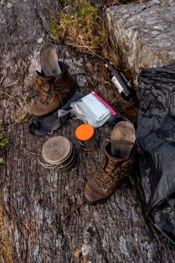 Kamp malzemeleri, yürüyüş ayakkabıları, sırt çantası, dağlarda bir taşın üzerinde bıçak.