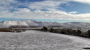 Parlak mavi gökyüzünün altındaki karla kaplı dağ manzarası. Manzaralı bir kış manzarasında yuvarlanan tepeler ve vadiler. Mavi gökyüzünün altında karla kaplı dağlarla nefes kesici bir kış manzarası..