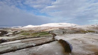 Göz kamaştırıcı bir manzara fotoğrafı karla kaplı dağlar ve dağınık bulutlu mavi gökyüzünün altındaki tarlalar, sakin bir kış manzarası yaratıyor..