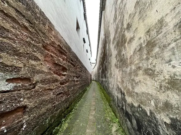 Eski yıpranmış duvarlarla dolu dar bir ara sokak uzaklığa çıkar, tarih ve mimari cazibeyi yakalar..