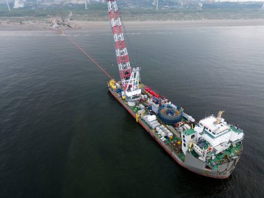 Bir gemi deniz kenarındaki bir rüzgar parkından Hollanda 'nın Wijk aan Zee kentindeki bir kıyı güç merkezine kadar açılır. Rüzgar tarlaları kablolar ya da borularla kıyı şeridine gidiyor.
