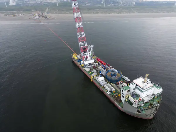 Bir gemi deniz kenarındaki bir rüzgar parkından Hollanda 'nın Wijk aan Zee kentindeki bir kıyı güç merkezine kadar açılır. Rüzgar tarlaları kablolar ya da borularla kıyı şeridine gidiyor.