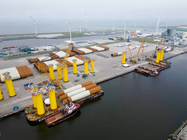 Defzijl, Hollanda - 26 Mayıs 2024 Kuzey Denizi 'nde deniz aşırı bir rüzgar parkı inşa etmek için çelik tekelleri taşıyan bir römorkör ve duba