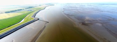 Bir gelgit kanalı ve Termunterzijl, Groningen, Hollanda yakınlarındaki çamurlu düzlükler.