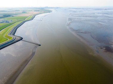 Bir gelgit kanalı ve Termunterzijl, Groningen, Hollanda yakınlarındaki çamurlu düzlükler.