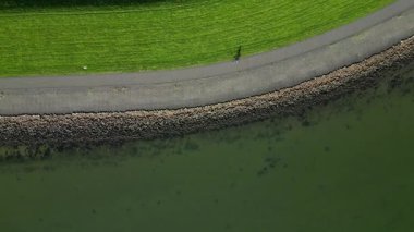 Açık deniz seviyelerine karşı koruyucu bir lezbiyenle bisiklete binen birinin hava görüntüsü, Hollanda.