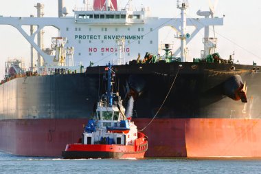 Rotterdam limanında bir römorkör ve büyük bir petrol tankeri görünüyor.