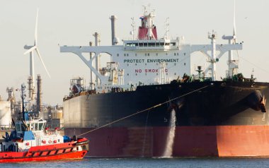 Rotterdam limanında bir römorkör ve büyük bir petrol tankeri görünüyor.