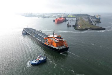 Rotterdam limanında büyük bir petrol tankeri ve römorkör manzarası var.