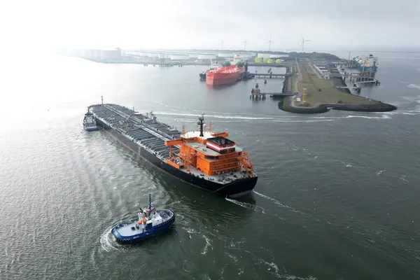 Rotterdam limanında büyük bir petrol tankeri ve römorkör manzarası var.