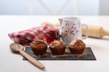 Kupalı muffinler ve tahta mutfak aksesuarlarıyla beyaz arka planda kırmızı bez..