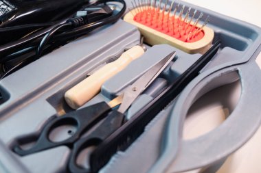 Farklı boyutlarda tarak, tıraş makinesi, fırça, makas ve tarak kesme seti olan bir köpek bakım çantasının ayrıntıları