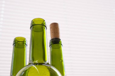 Tarafsız ışık arka planında yeşil şarap şişeleri olan kompozisyon