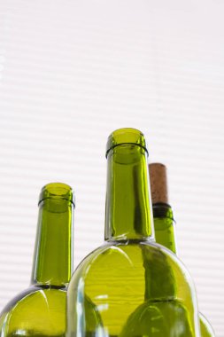 Tarafsız ışık arka planında yeşil şarap şişeleri olan kompozisyon