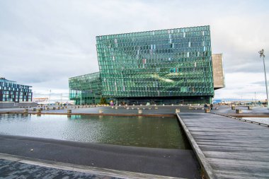 Reykjavk, İzlanda 'daki Harpa Konser Salonu, sakin deniz kıyılarına yansıdı. Modern cam mimarisi ve geometrik tasarım sakin kıyı ayarı karşısında duruyor..