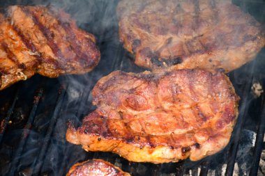 Mangalda ızgara domuz bifteği ve yakın çekim sahnesinde duman ve kireç hatları.