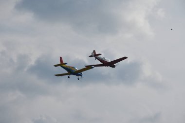 Bir havacılık olayı sırasında bulutlu bir gökyüzünün altında iki hafif akrobatik uçak gevşek bir düzende uçar..