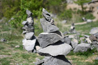 Çimenli bir açık havada yakalanmış, özenle dengelenmiş gri taşlar yığını doğadaki odak, denge ve farkındalığı sembolize ediyor..