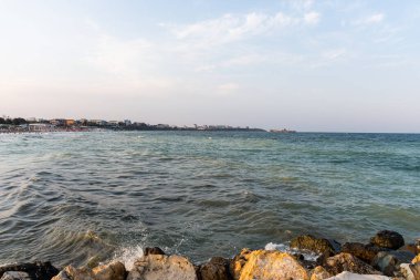 Karadeniz kıyı şeridinin manzarası yumuşak akşam ışığı altında kayalara, plajlara ve ufka vuran dalgalarla dolu..