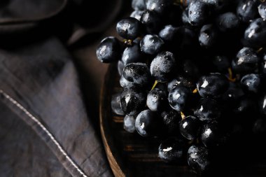 Koyu arkaplanda, ahşap bir masada üzüm.