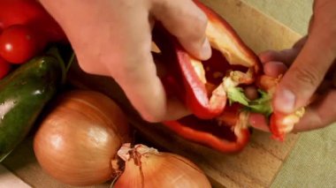 Erkek eller yeşil dolma biberi açar ve tahtadan kesilmiş tahtadan soğan ve sebzelerle tohum çıkarır. Yeşil dolma biber doğal dokuyu gösterir. Ev yapımı yemekler için aşçılık hazırlama süreci kavramı
