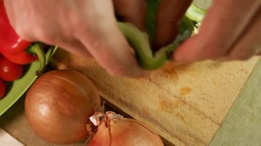 Erkek elleri ahşap kesme tahtasındaki yeşil dolmalık biberi temizler. Yeşil dolma biber tazeliği ve doğal dokuyu gösterir. Sağlıklı ev yemekleri için malzeme hazırlama kavramı.