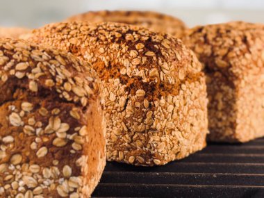 Soğutma rafında sergilenen altın kabuklu taze pişmiş yulaf ekmeği desenli yüzeyin yakın çekim görüntüsünü sunuyor..