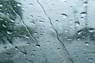 Yağmur yağdığında ön cama düşen su damlalarının resmi. Yağmur yağdığında yoldaki arabayı kullan. Yağmur mevsimi havası. Gitmeden önce havayı kontrol et. Şiddetli yağmur, yolu göremiyorum.. 