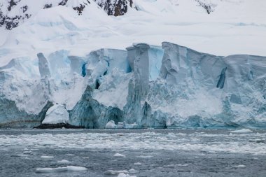 Adelie pengueni (Pygoscelis adeliae) Antarktika yarımadasında. Karda dikilip kameraya bakıyorum. Yüzgeçler geniş açılır. Penguen izleri karların arkasında. 