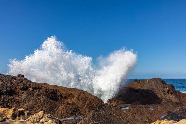 Point Lobos Doğa Koruma Alanı, Monterey, Kaliforniya 'da kaya kırılması. Havaya püskürt. Mavi gökyüzü, arka planda Pasifik okyanusu. 