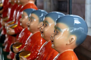 Tayland, Bangkok 'taki Wat Rakhang Tapınağı' ndaki keşişleri resmeden heykeller. Kırmızı cüppeli, altın kaseli, tıraşlı başlıklı.. 