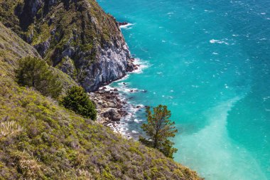 Pasifik Sahil Otoyolu boyunca kıyı şeridi, Monterey, California 'nın güneyi. Uçurumun aşağısına bak; mavi-yeşil su, küçük kayalık plaj.