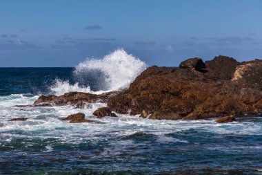 Monterey, California 'daki Point Lobos Eyalet Konservesi' nde dalgalar kırılıyor. Arka planda mavi gökyüzü. 