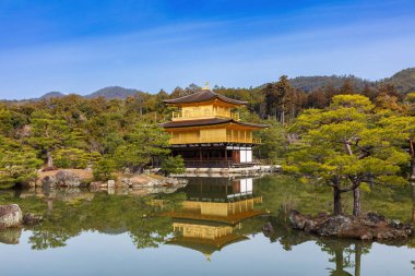 Altın Pavyon (Kinkaku-ji), Japonya, Kyoto 'da. Gölün karşısına bakarken; pavyon su yüzeyinde yansıtılır. En üstteki iki kat gerçek altınla kaplı.. 
